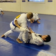 Two men practicing judo on a blue floor.