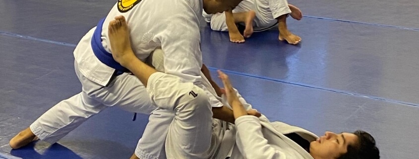 Two men practicing judo on a blue floor.