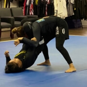 Two people are wrestling on a blue mat.