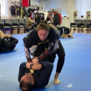 A woman is wrestling another man on the floor.