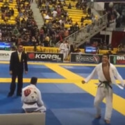 A man in white shirt and black pants standing on a mat.