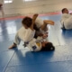 A group of kids practicing martial arts in an indoor gym.