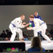 Three men in blue and white uniforms are on a stage.