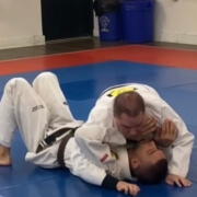 Two kids are wrestling on a mat in the gym.