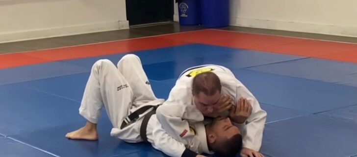 Two kids are wrestling on a mat in the gym.