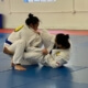 Two girls are practicing jiu jitsu on a blue floor.