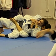 Two people are practicing jiu jitsu on a mat.