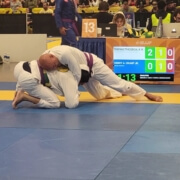 A man in white and black uniform on blue mat.