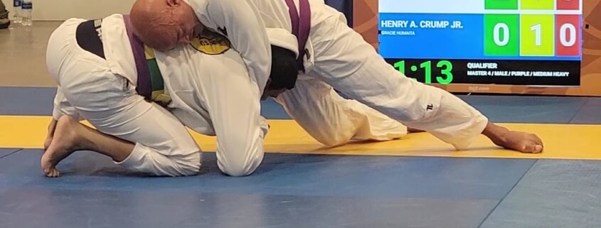 A man in white and black uniform on blue mat.