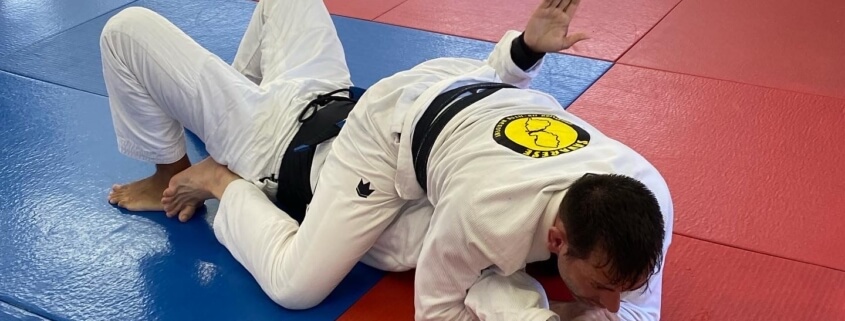 A man in white and black uniform on red mat.