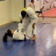 A man and woman are practicing judo on the floor.