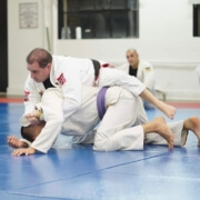 Two men are practicing judo on a blue floor.