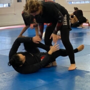 Two women are practicing jiu jitsu on a blue floor.