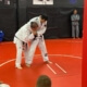 Two men in white uniforms practicing judo on a red mat.