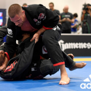 A man in black and red uniform on blue mat.