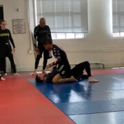 A man is wrestling on the ground in an indoor gym.