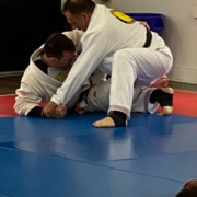Two people are wrestling on a mat in the gym.