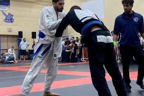 Two men in a judo match, one of them trying to kick another man.