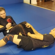 Two men are practicing jiu jitsu on a blue mat.