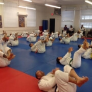 A group of people in white uniforms doing sit ups.