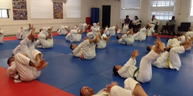 A group of people in white uniforms doing sit ups.